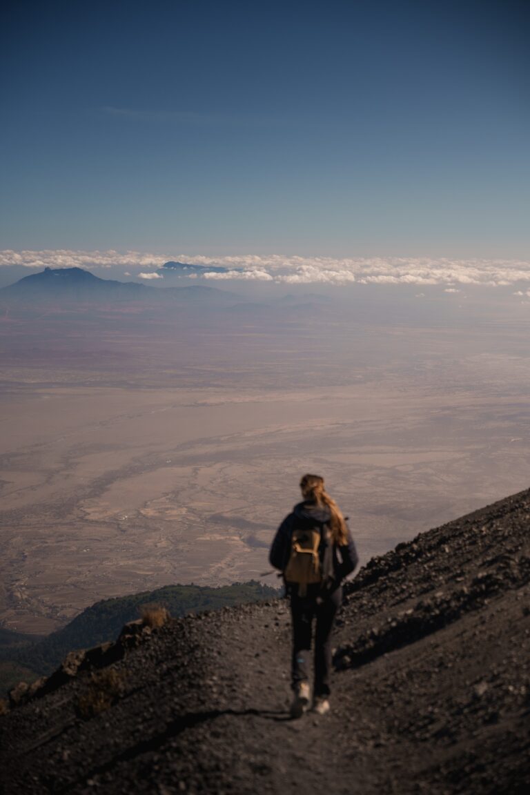 Hiker walking on mount meru ash cone with kilimanjaro in background